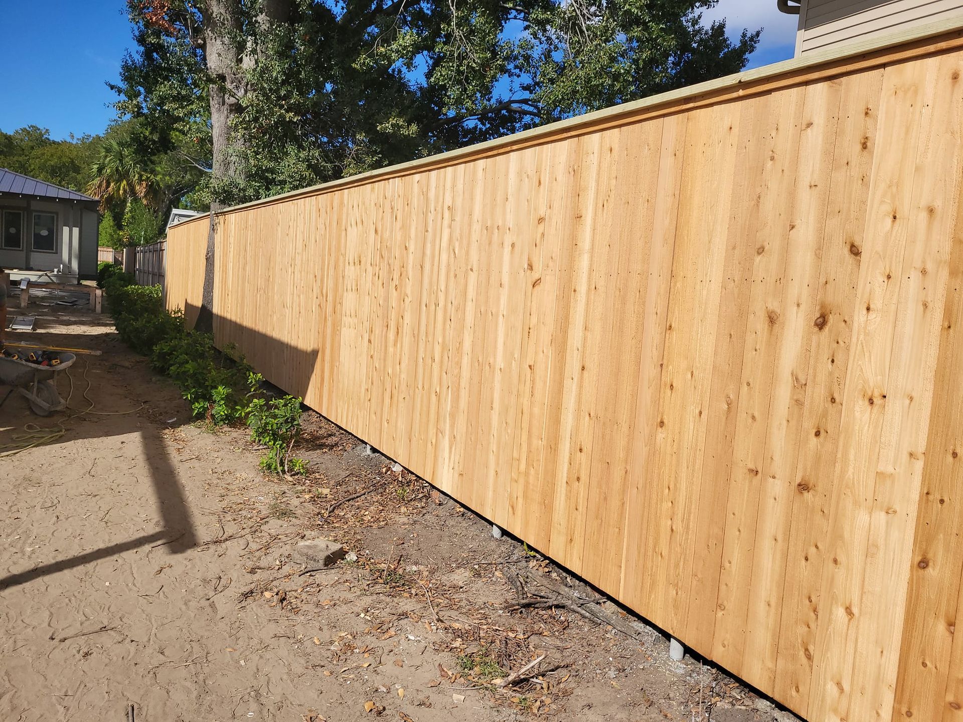 A wooden fence is sitting in the dirt in front of a house.