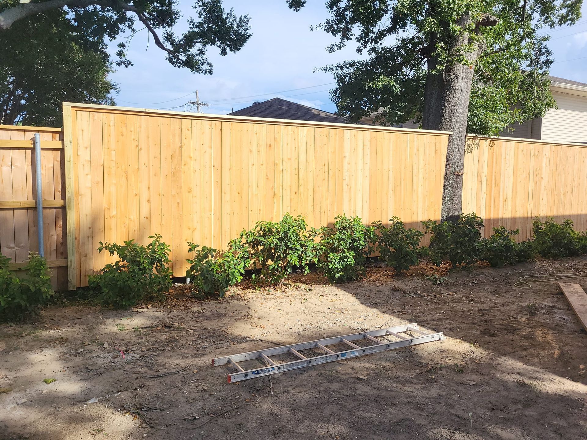A wooden fence is being built in a backyard