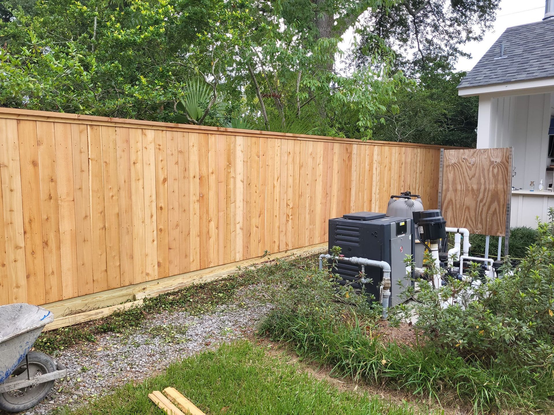 A wooden fence is being built in the backyard of a house.