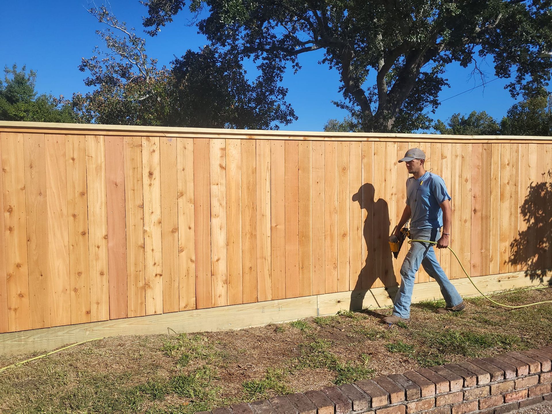 A man is walking in front of a wooden fence