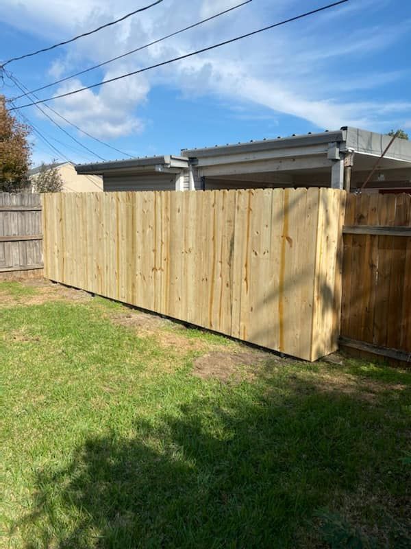 A wooden fence is in the backyard of a house.