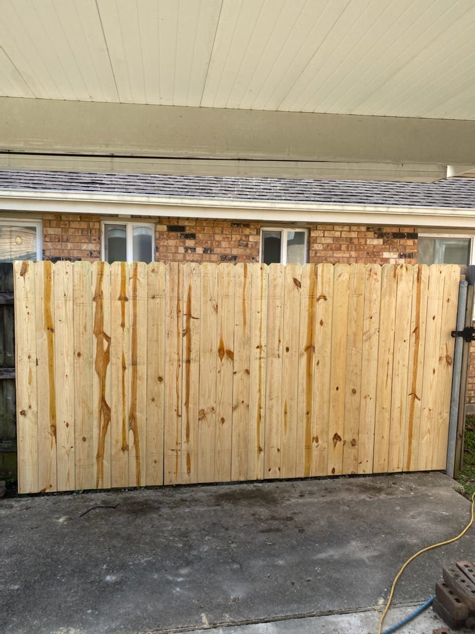 A wooden fence is sitting in front of a brick house.