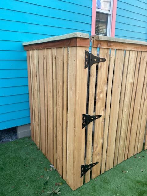 A wooden fence is sitting in front of a blue house.