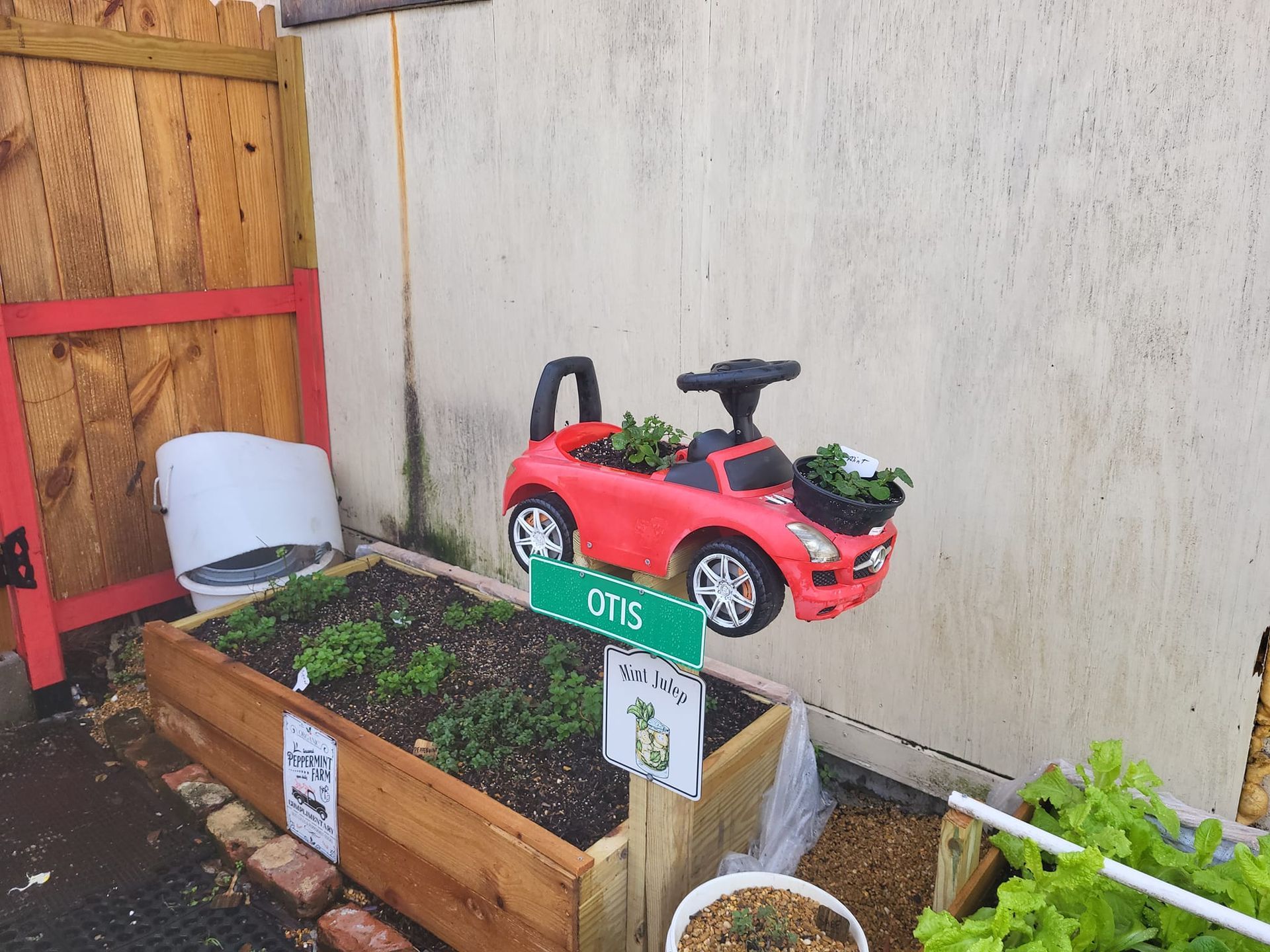 A red toy car is sitting on top of a wooden planter.