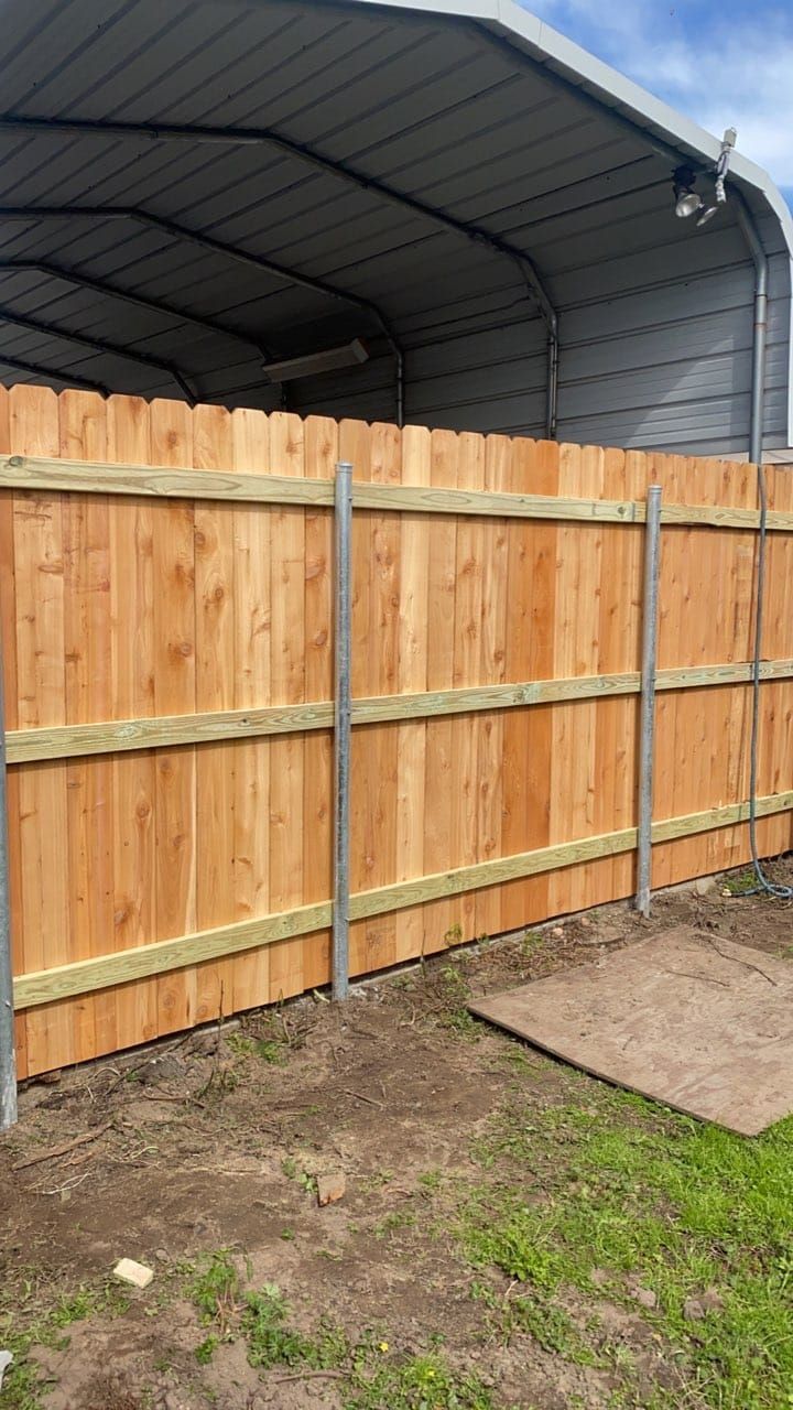 A wooden fence is sitting in front of a garage.