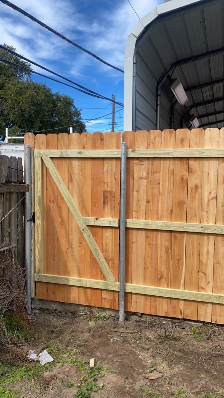 A wooden fence with a gate in front of a garage.