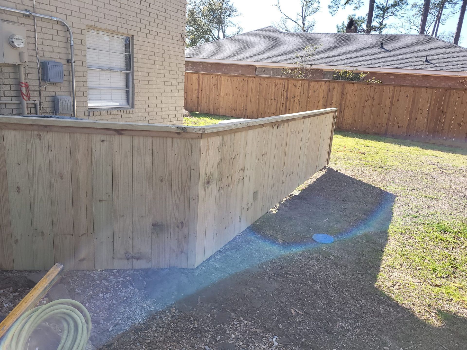 A wooden fence is in the backyard of a house.