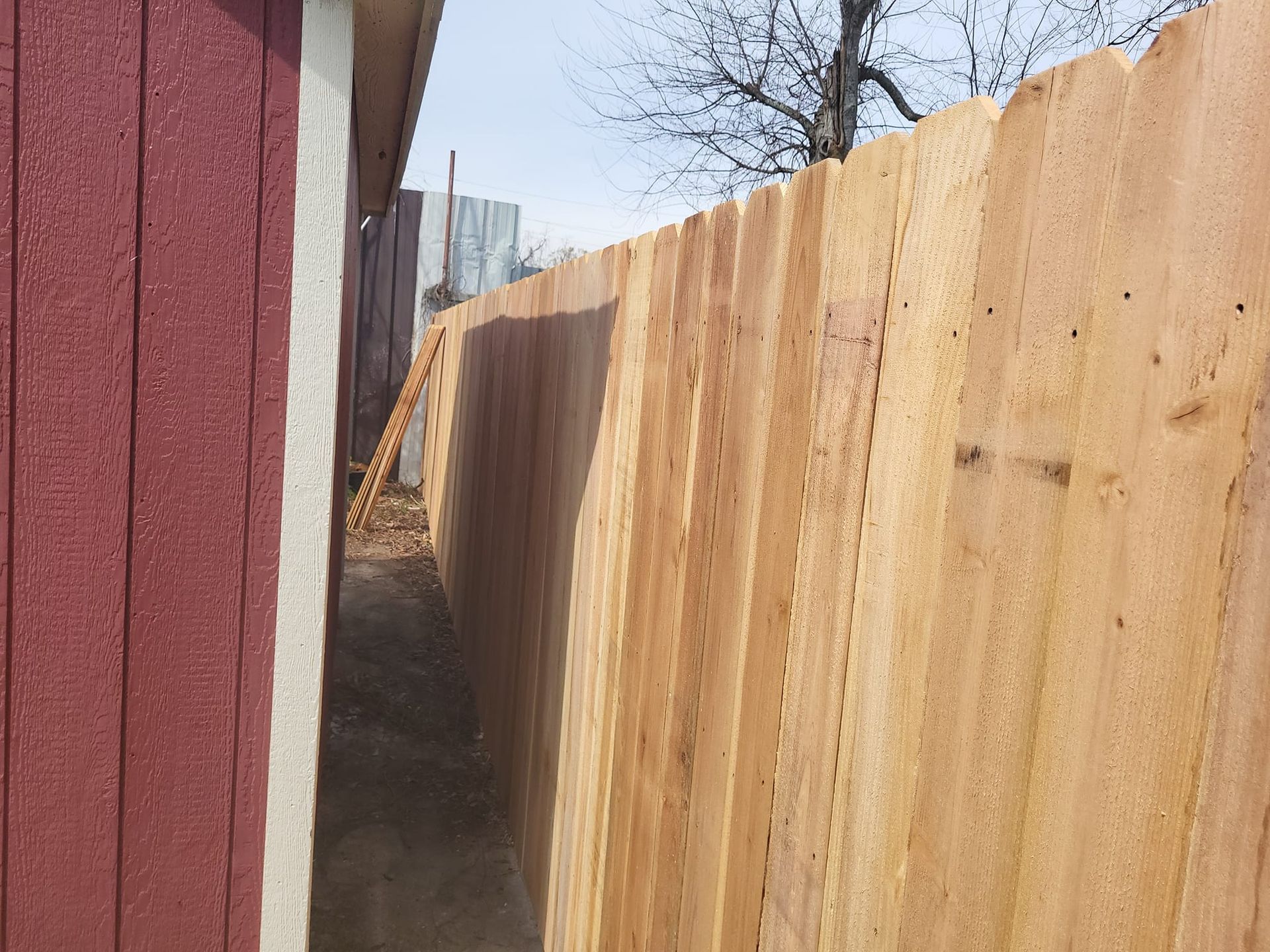 A wooden fence is next to a red building.