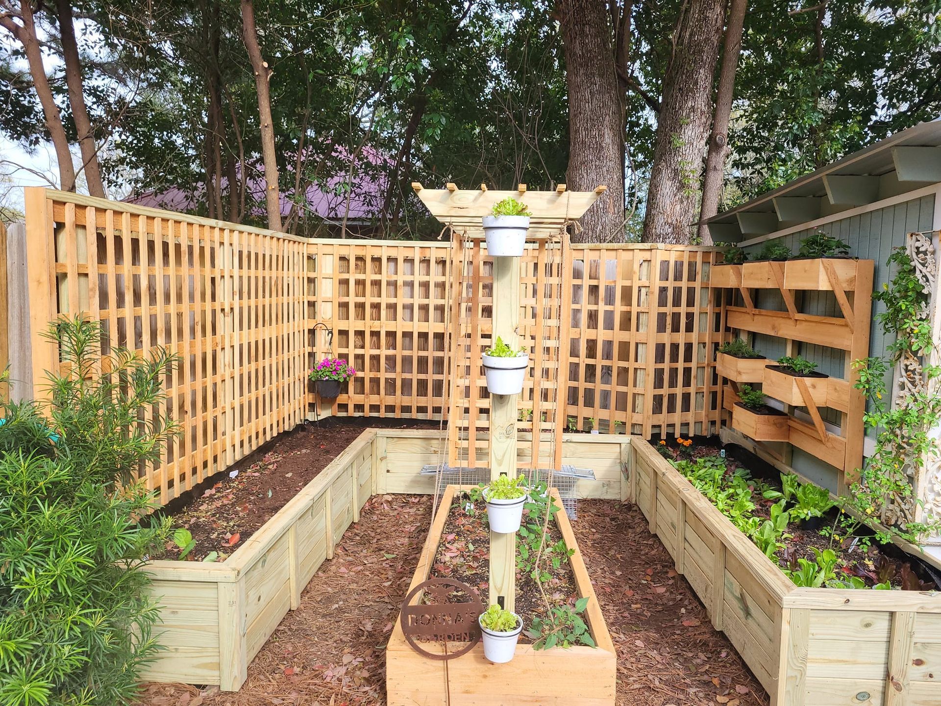 A wooden garden with lots of potted plants and a wooden fence.