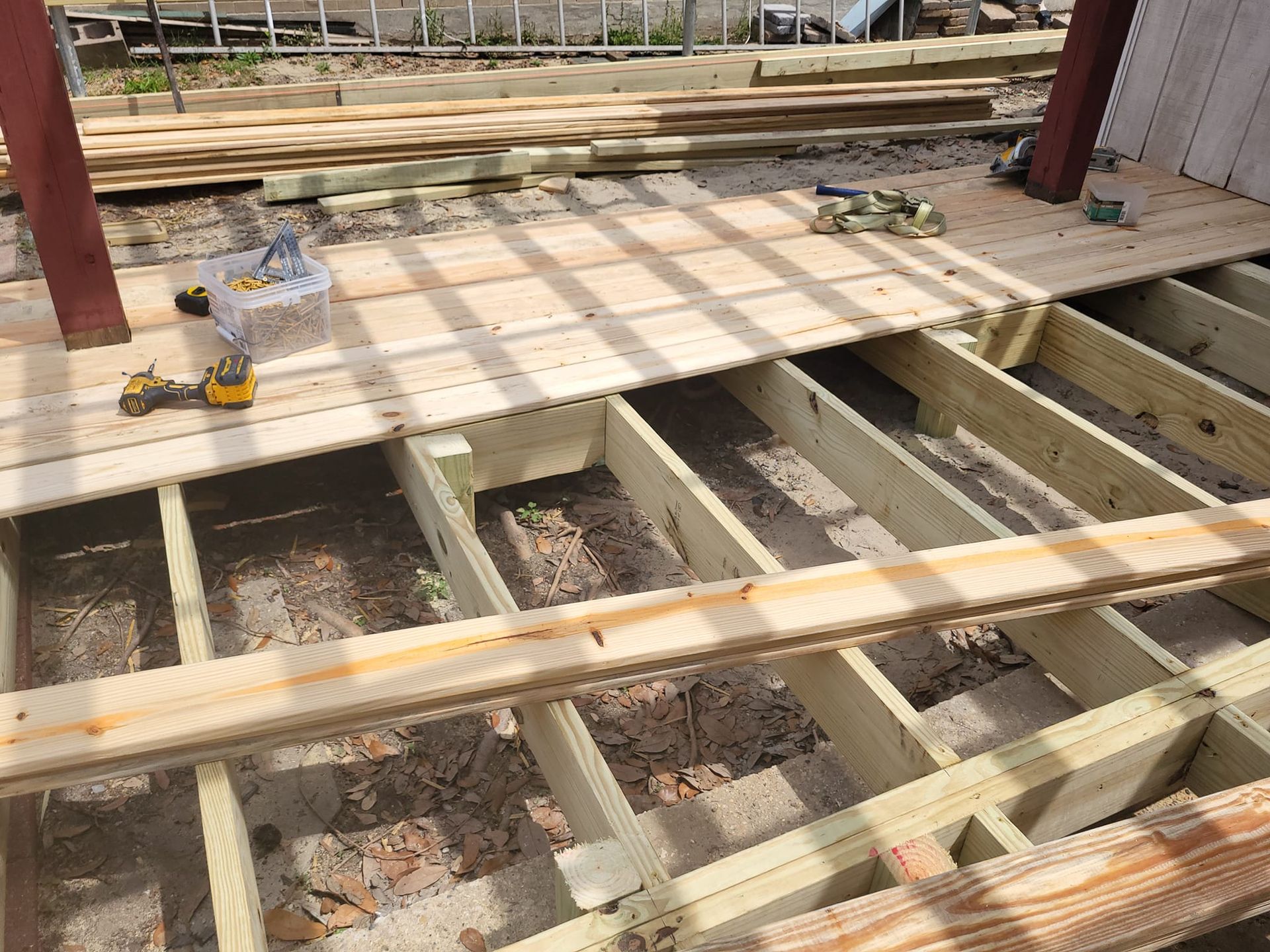 A wooden deck under construction with a drill on top of it.