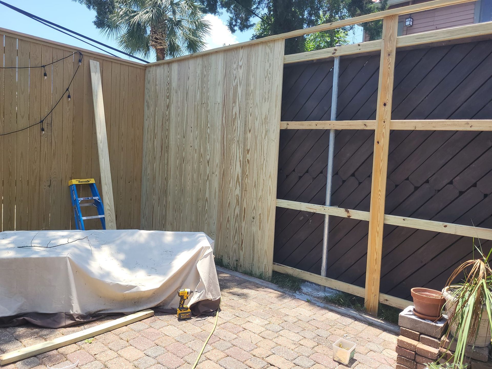 A wooden fence is being built in a backyard.