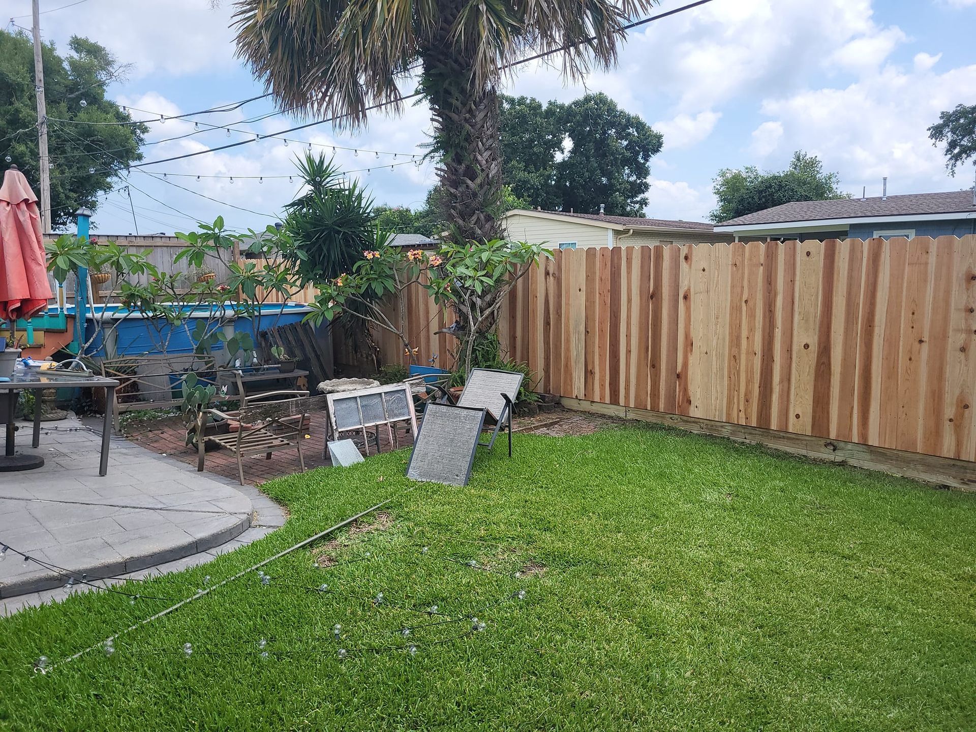 A backyard with a wooden fence and a patio area.