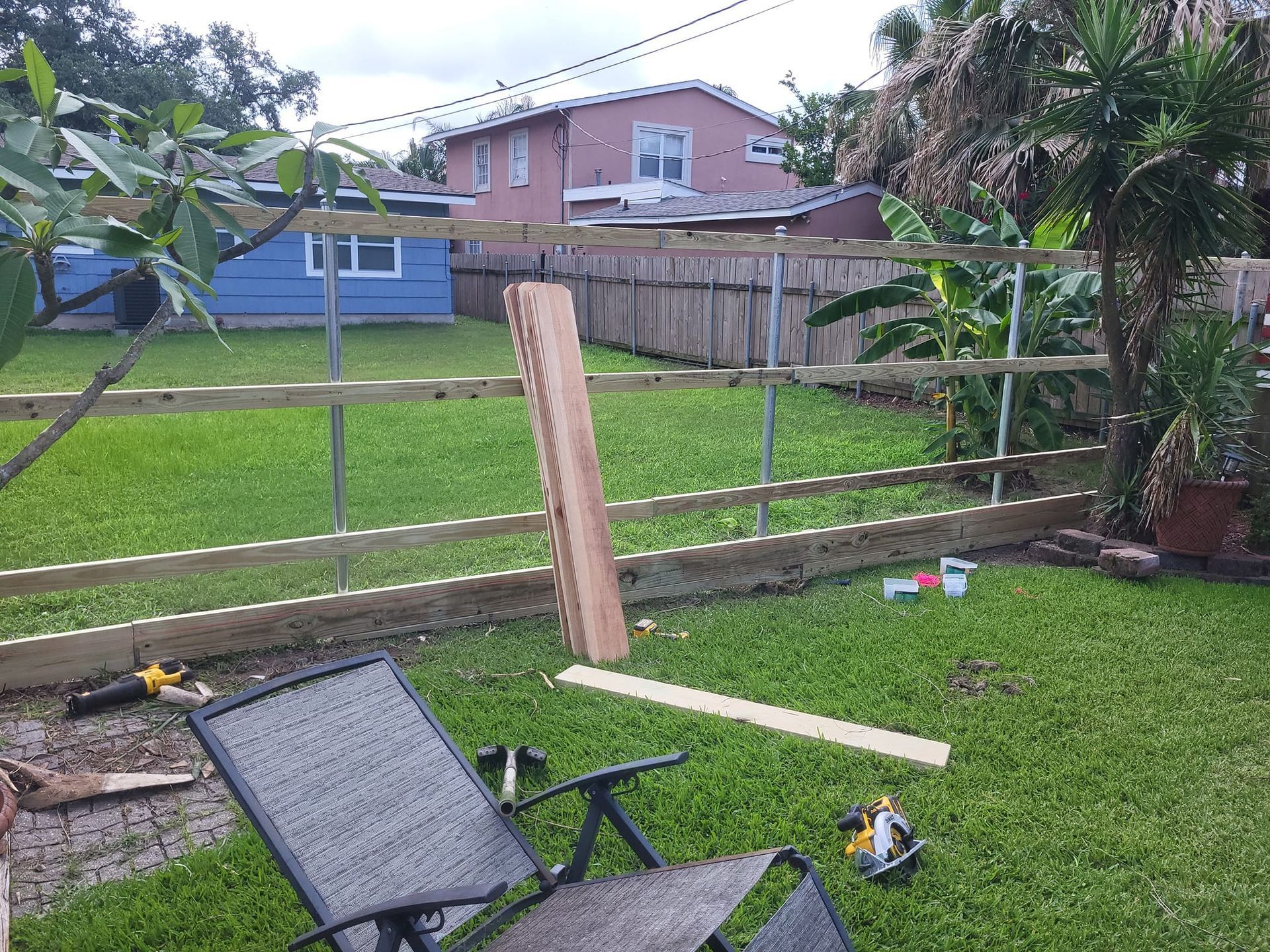 A wooden fence is being built in the backyard of a house