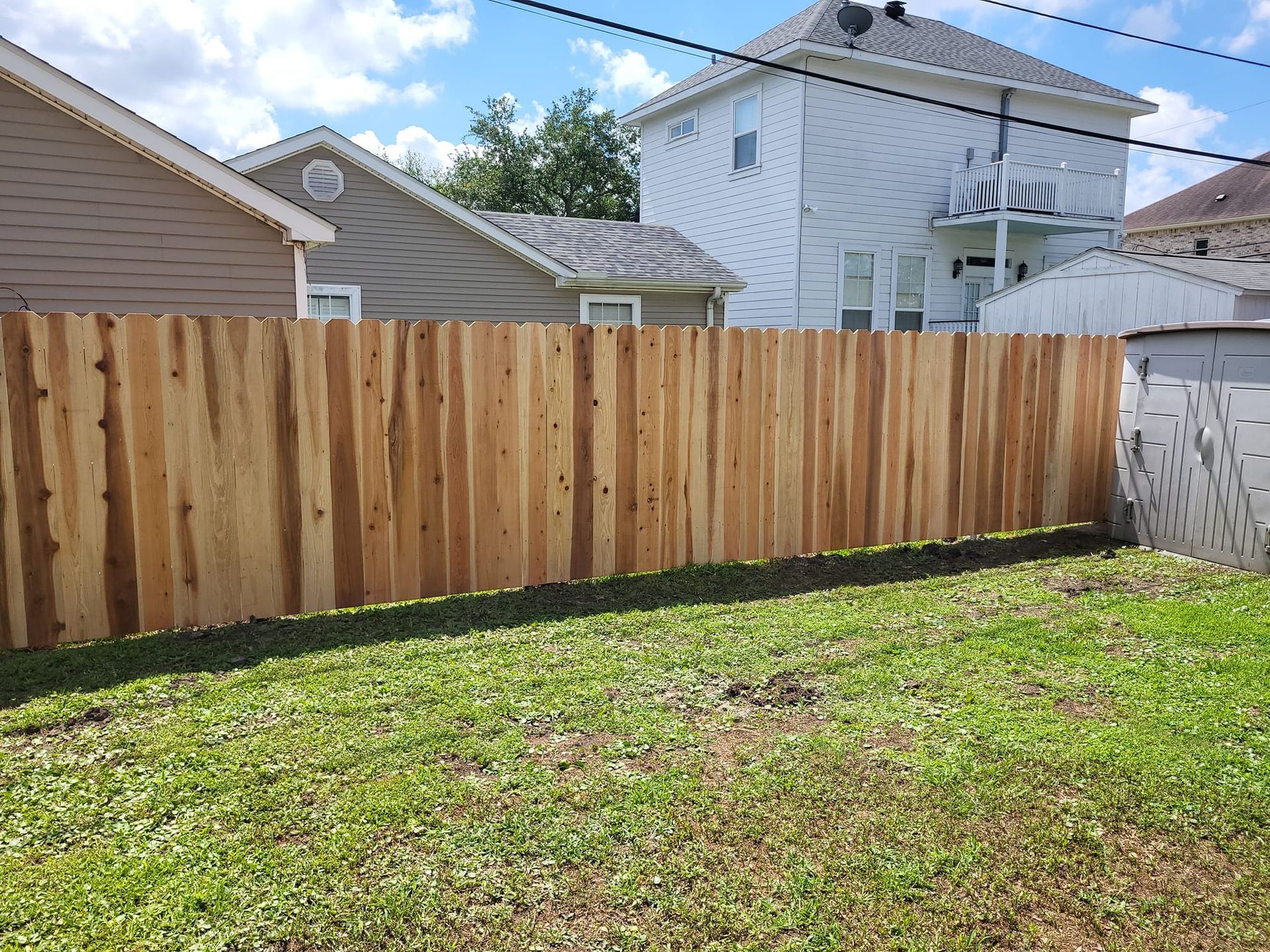 A wooden fence is in the backyard of a house.