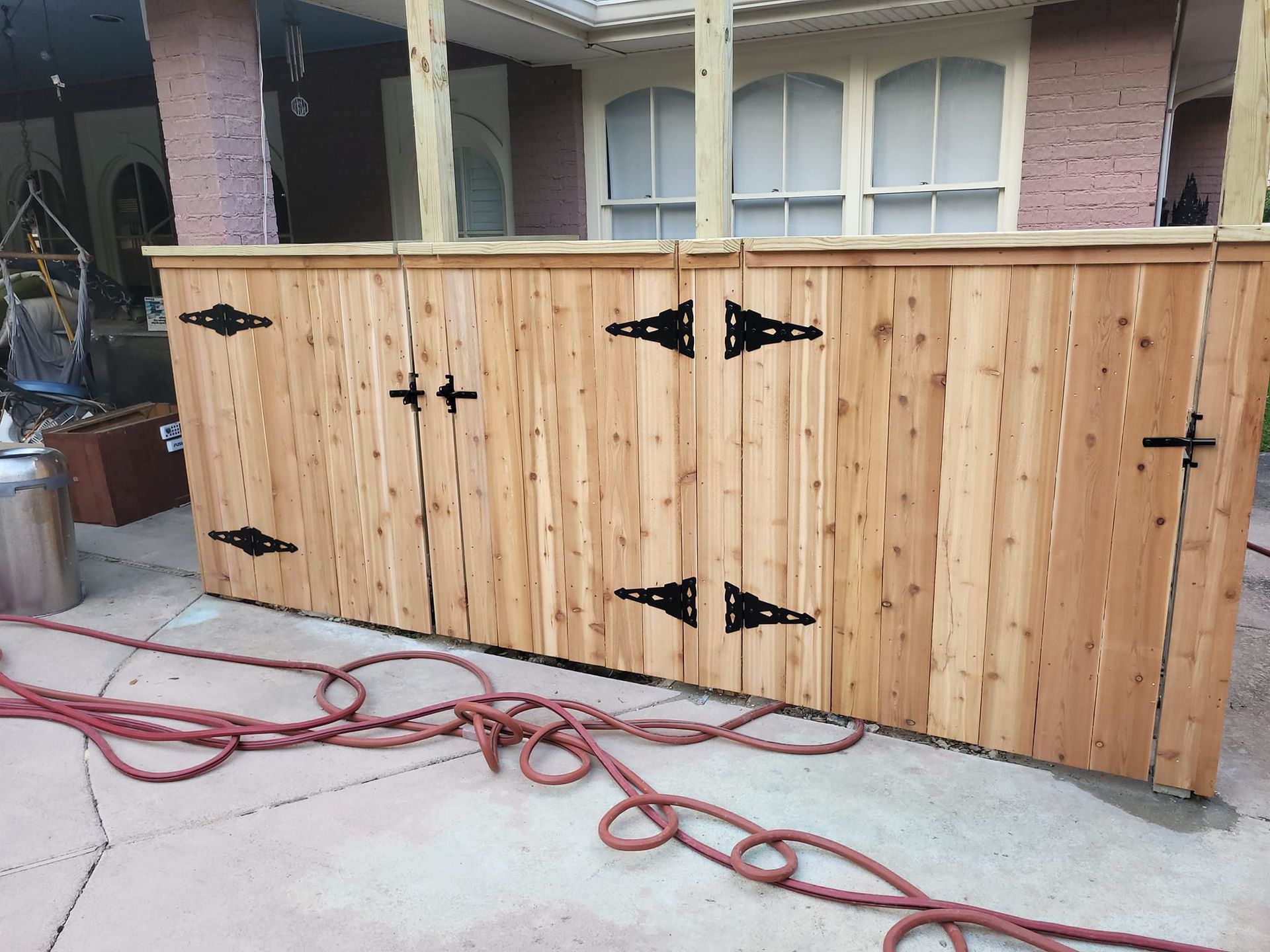 A wooden fence with black hinges is sitting on the sidewalk