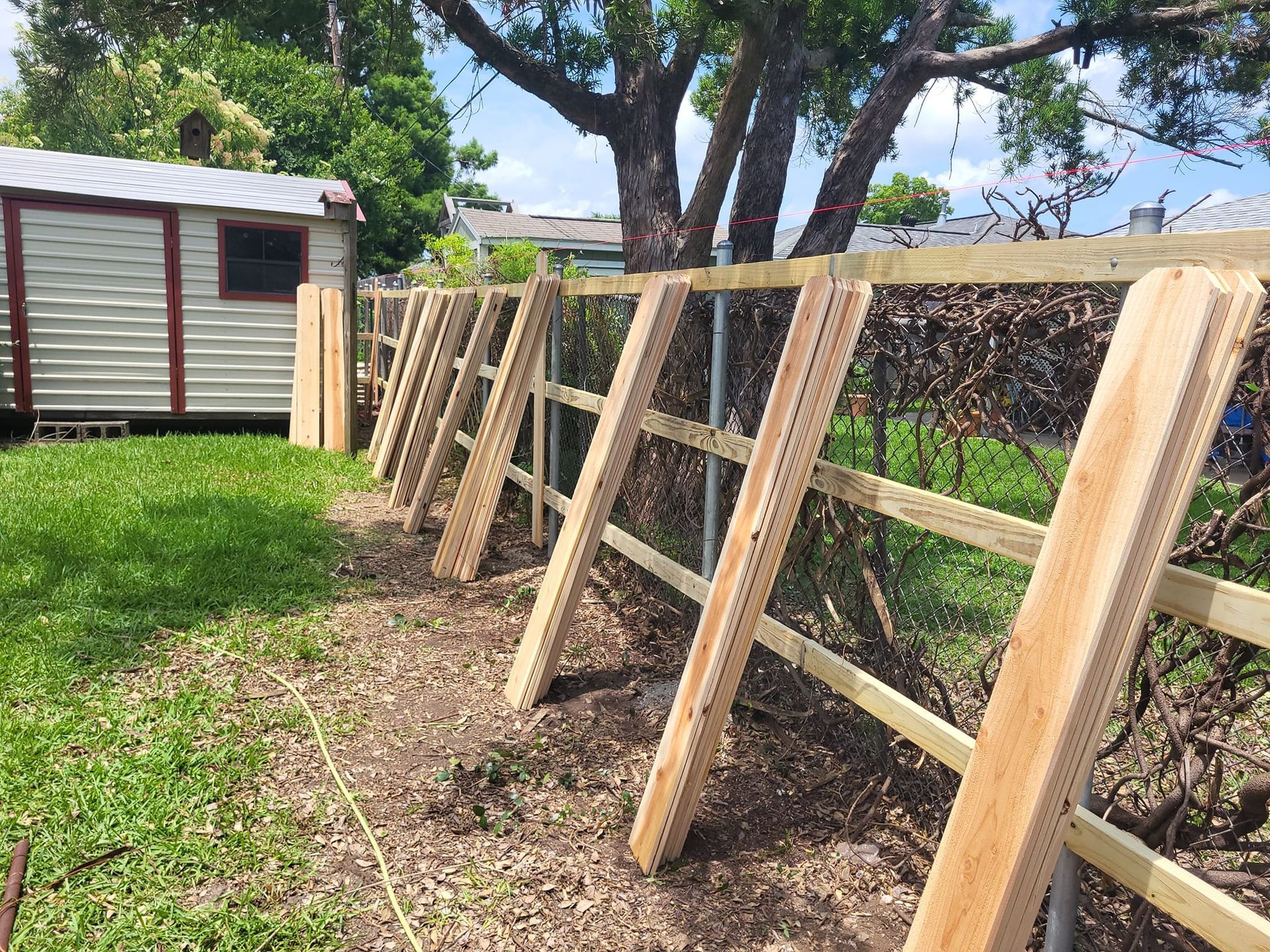 A wooden fence is being built in a backyard.