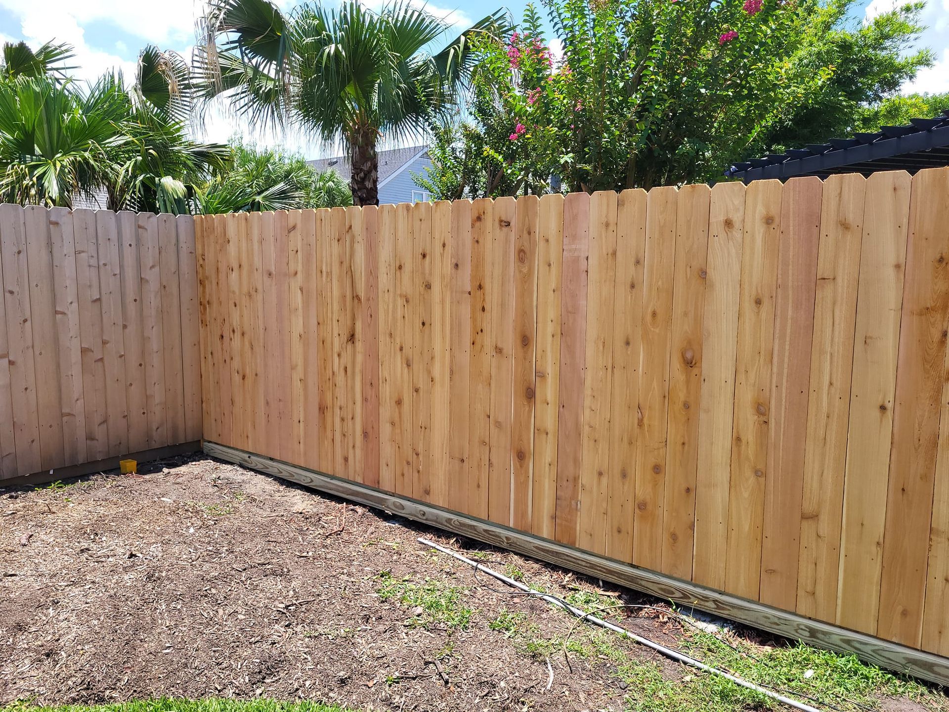 A wooden fence is in the backyard of a house.