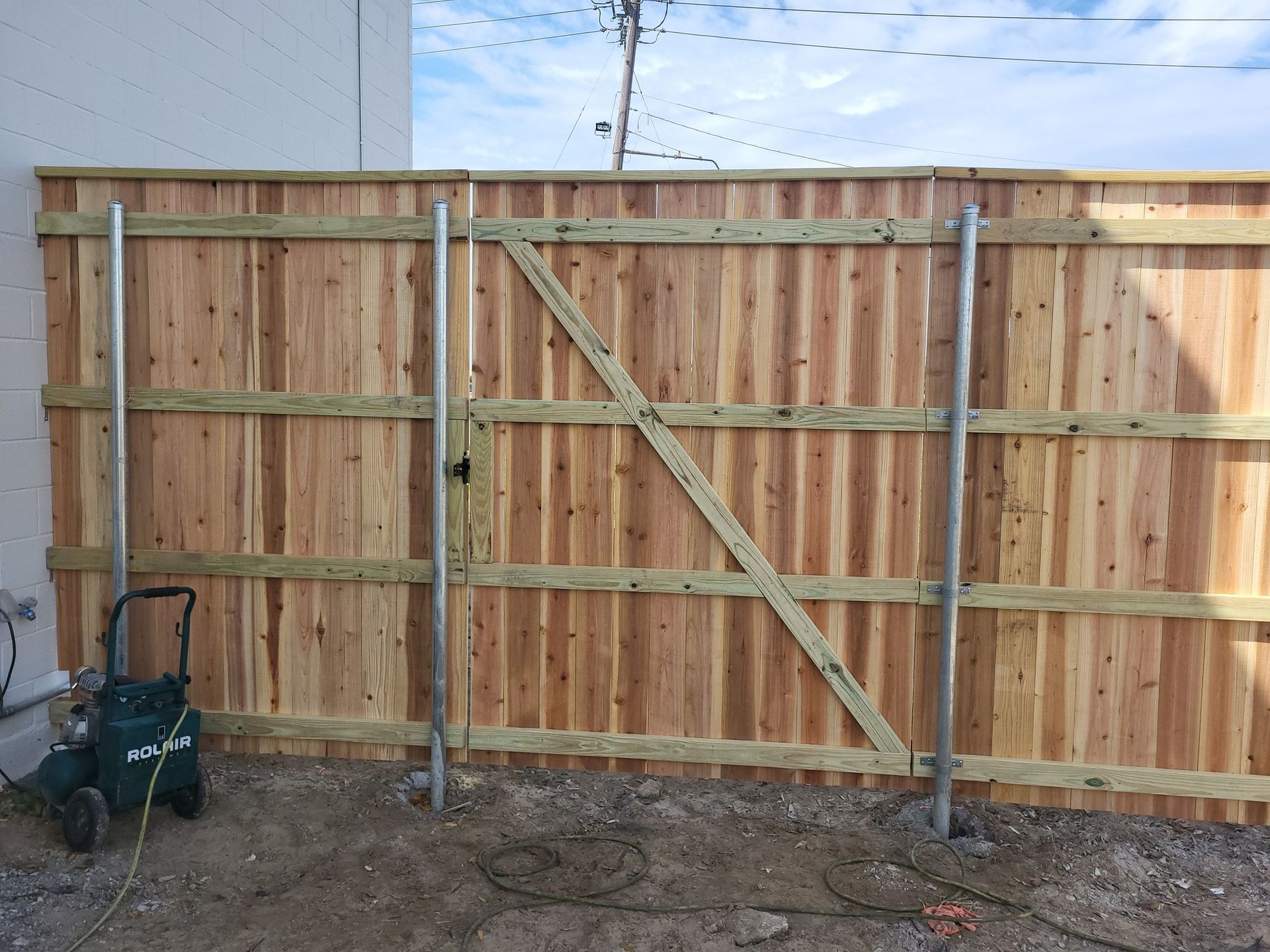 A wooden fence with a green wheelbarrow in front of it