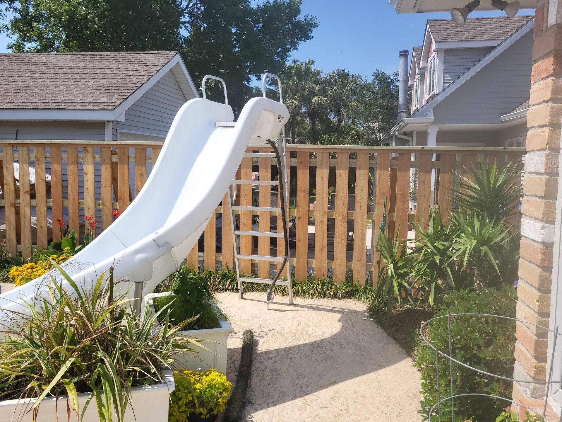 A white slide with a wooden fence behind it