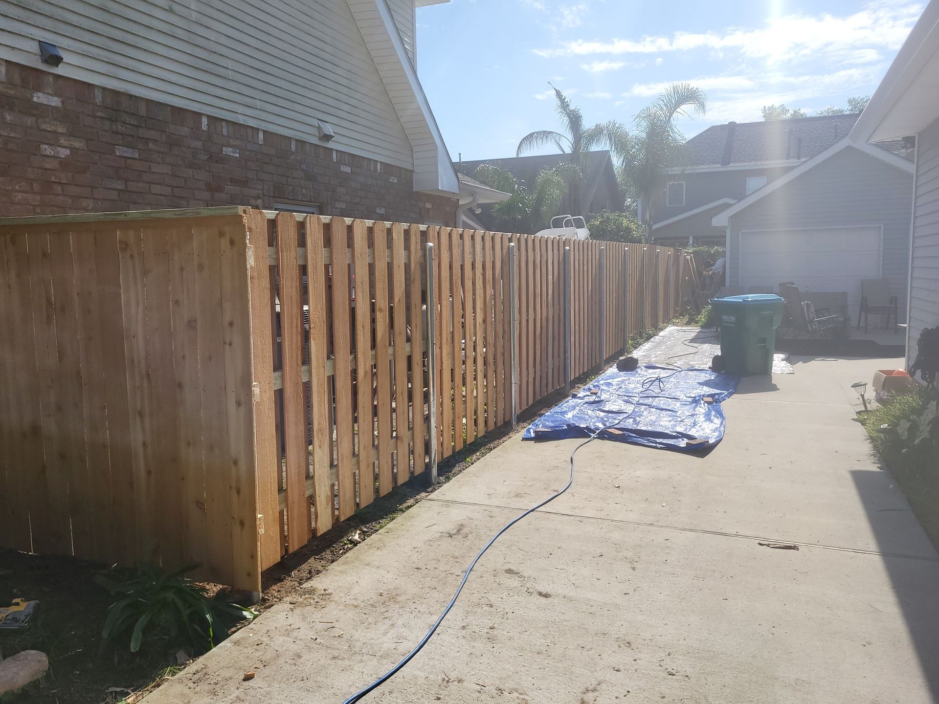 A wooden fence is being built in a driveway next to a house.