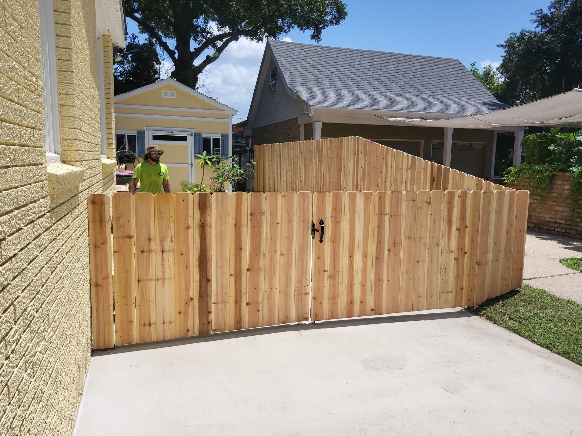 Wooden fence with a gate near a house; person in the background.