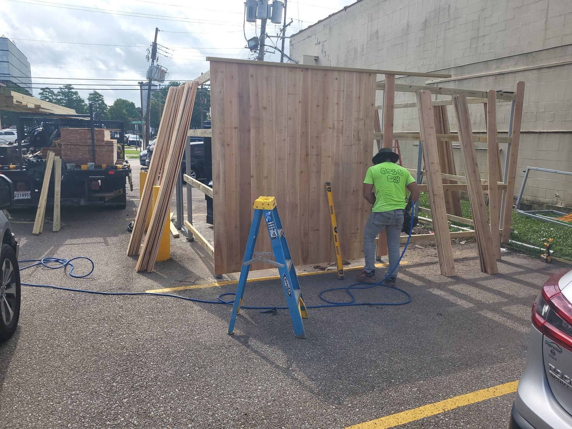 A man is working on a wooden structure in a parking lot.