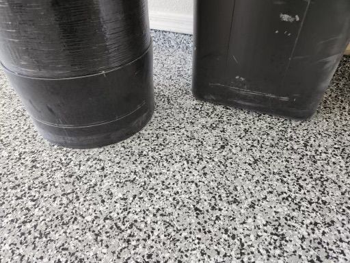 two black barrels are sitting on a gray and white floor .