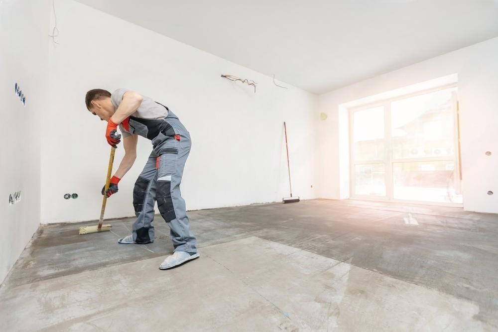 a man is cleaning the floor with a broom in an empty room .