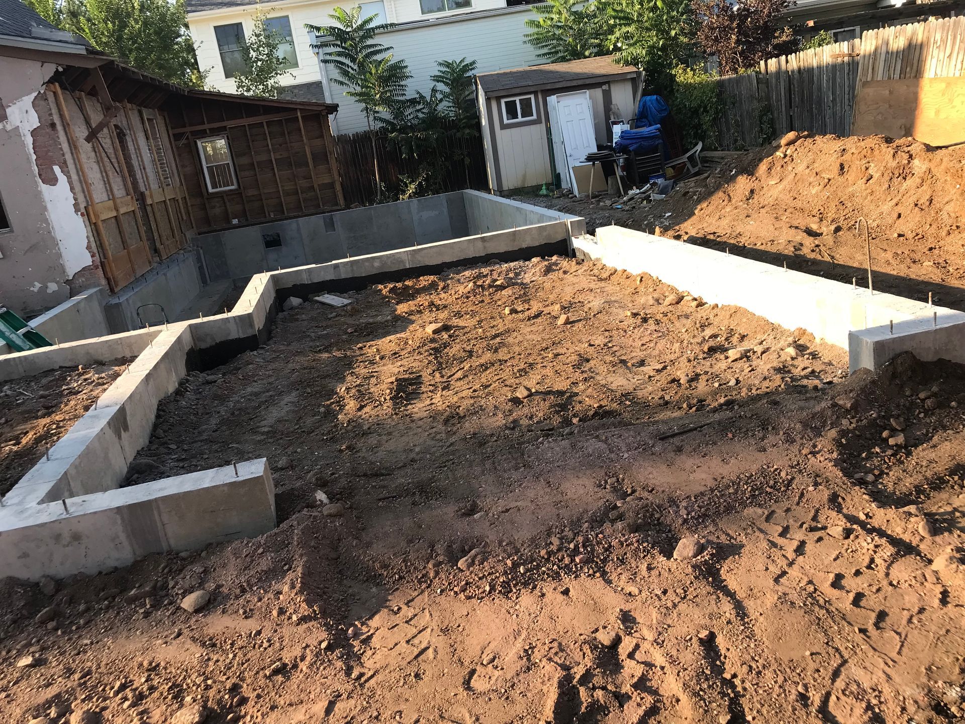 A man wearing a hard hat and overalls is digging with a shovel in a room.