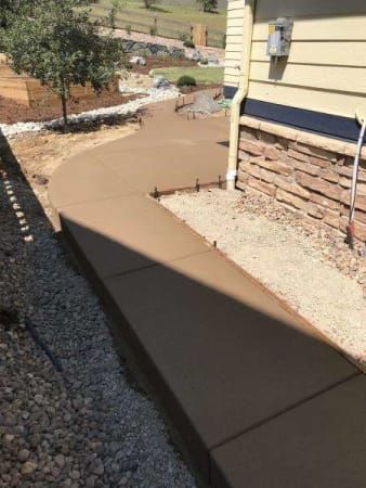 A concrete walkway is being built in front of a house.