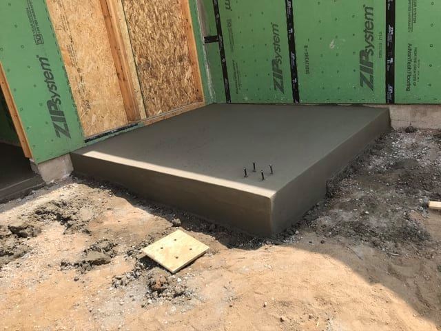 A concrete slab is being built in front of a green wall.