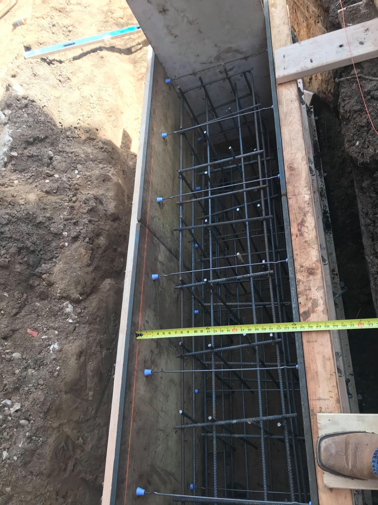 A person is measuring a concrete wall with a tape measure.