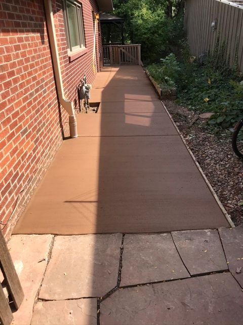 A brick house with a concrete walkway leading to it.