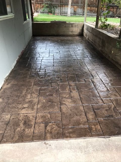 A patio with a concrete floor and a fence in the background.