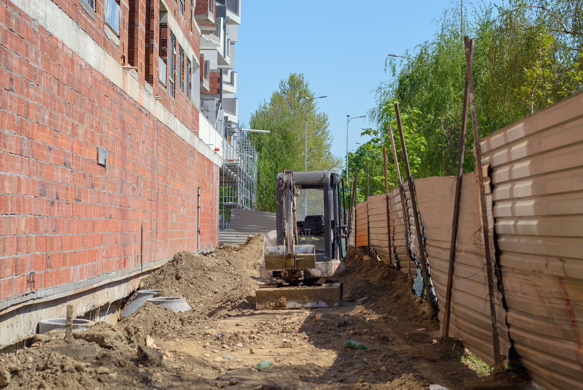 A bulldozer is parked on a dirt road in front of a building under construction.