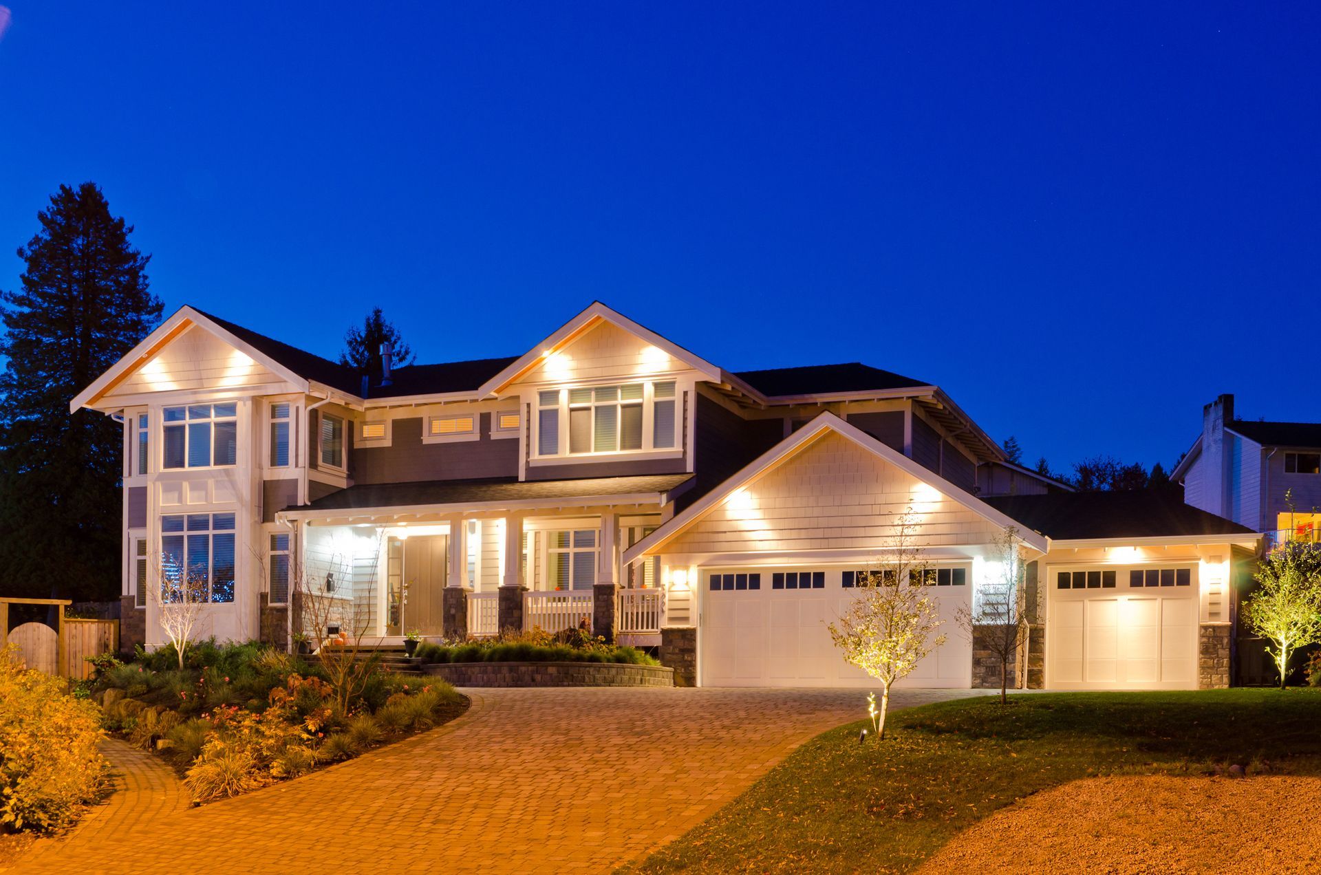 A large house is lit up at night in a residential area
