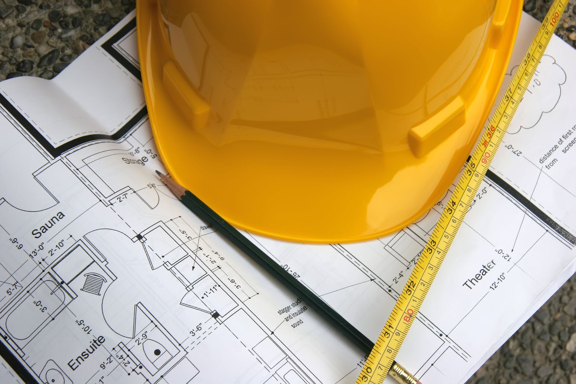 A yellow hard hat sits on top of a blueprint