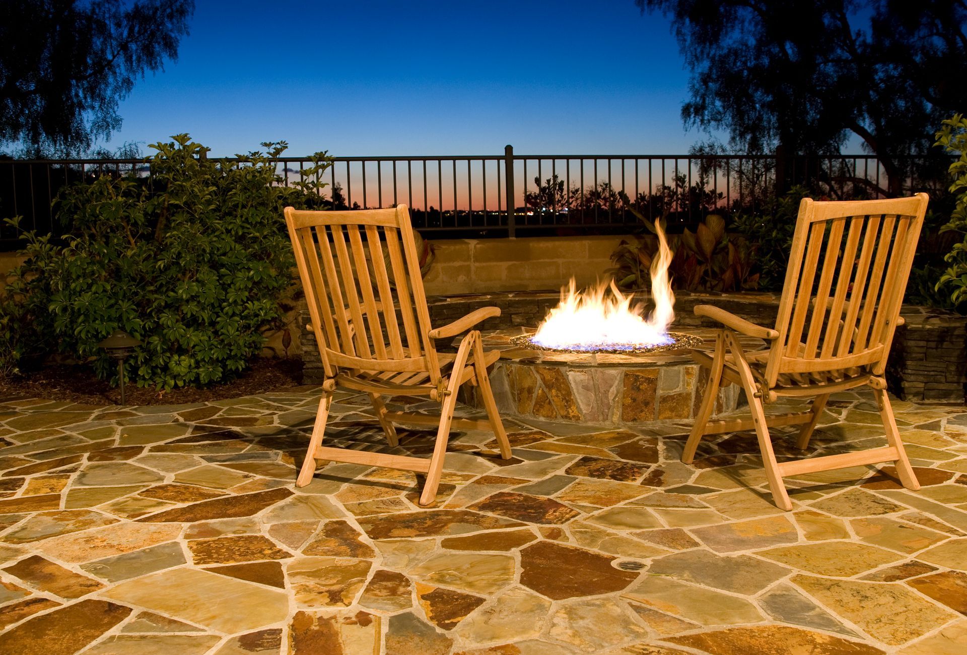 Two chairs are sitting next to a fire pit on a patio.