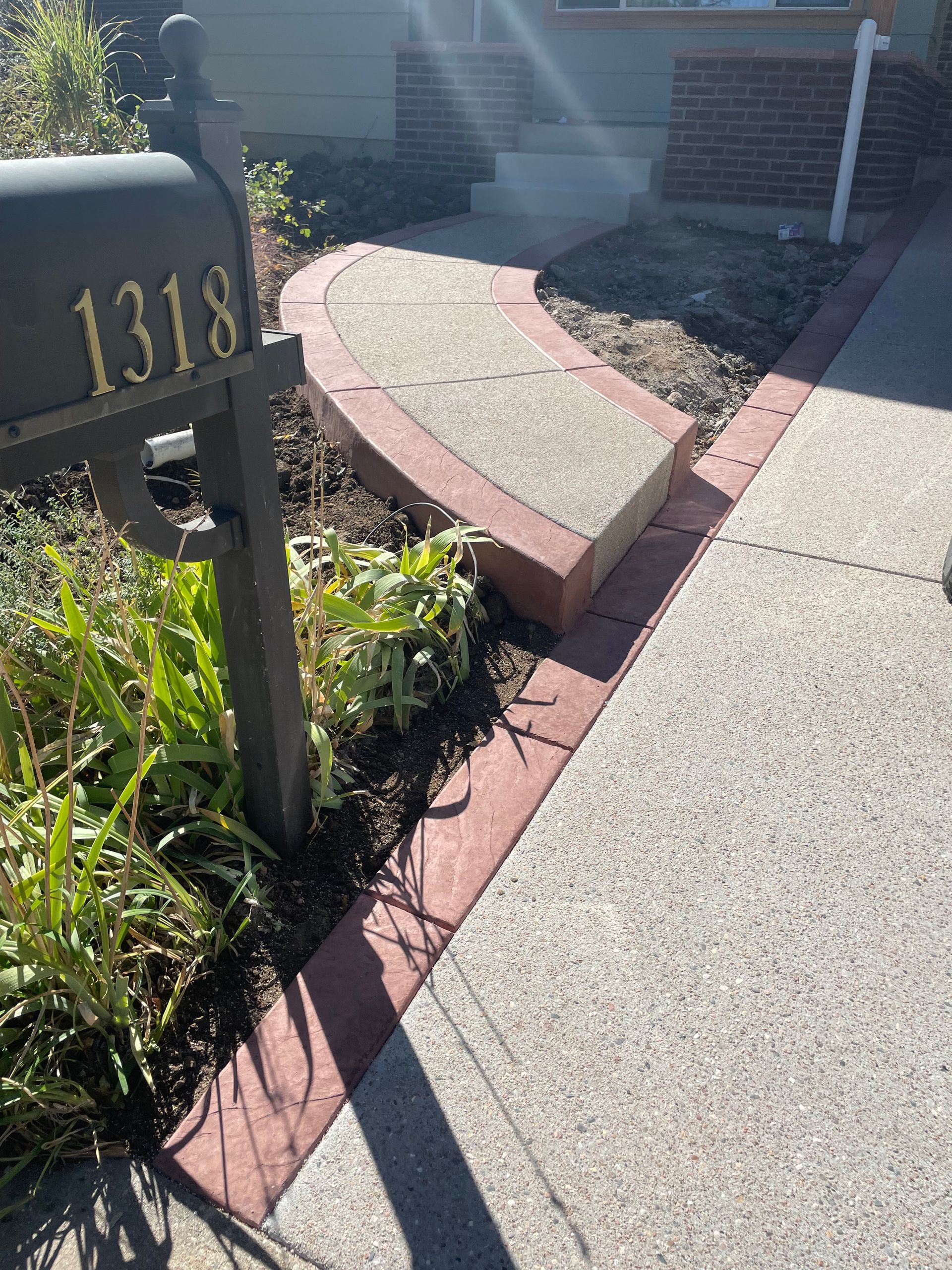 A mailbox with the number 1318 on it is next to a sidewalk.