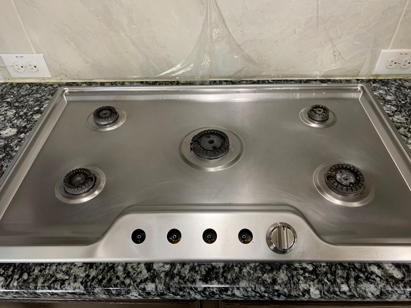 A stainless steel stove top oven is sitting on top of a granite counter.