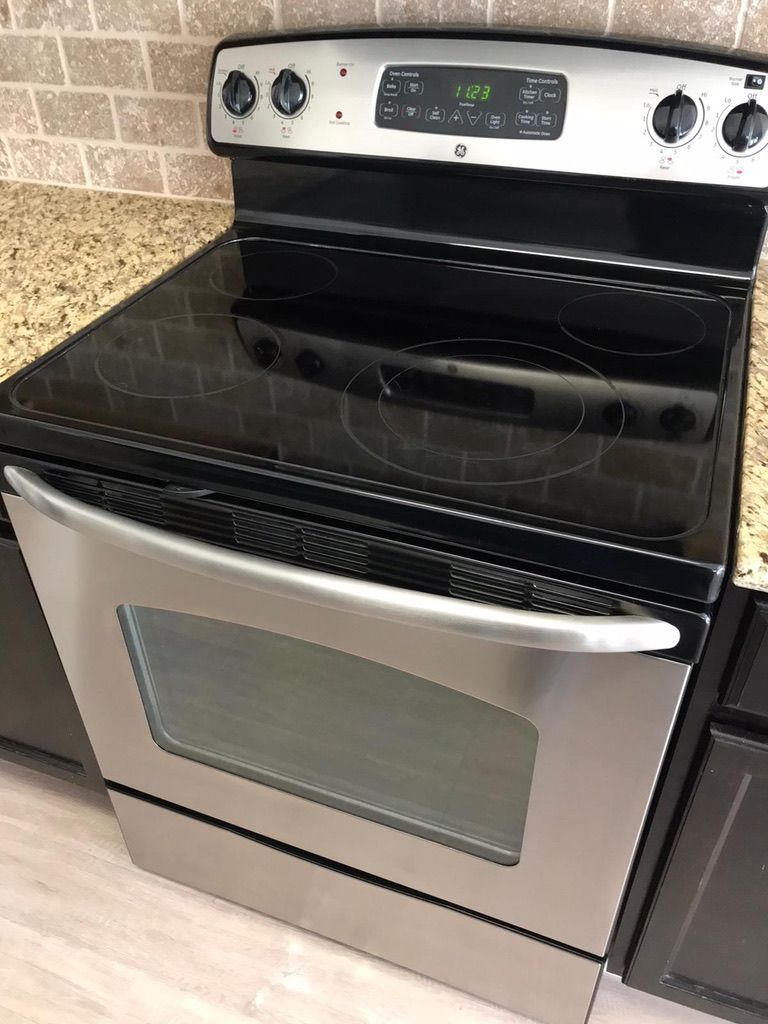 A stainless steel stove top oven is sitting on top of a granite counter in a kitchen.