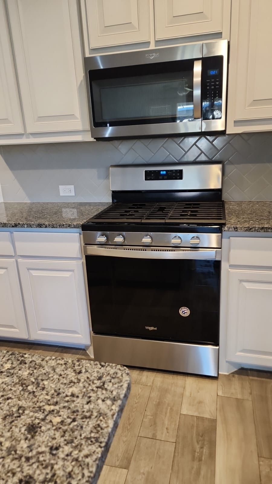 A stainless steel stove and microwave are in a kitchen.