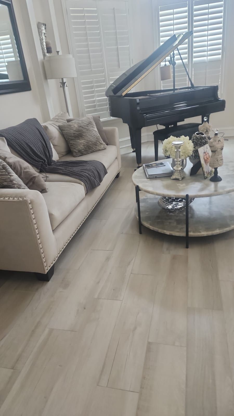 A living room with a couch , coffee table , and piano.