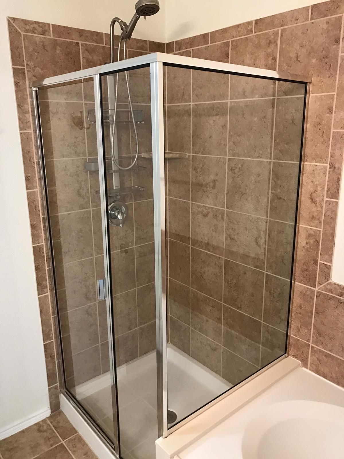 A bathroom with a glass shower stall and a shower head.