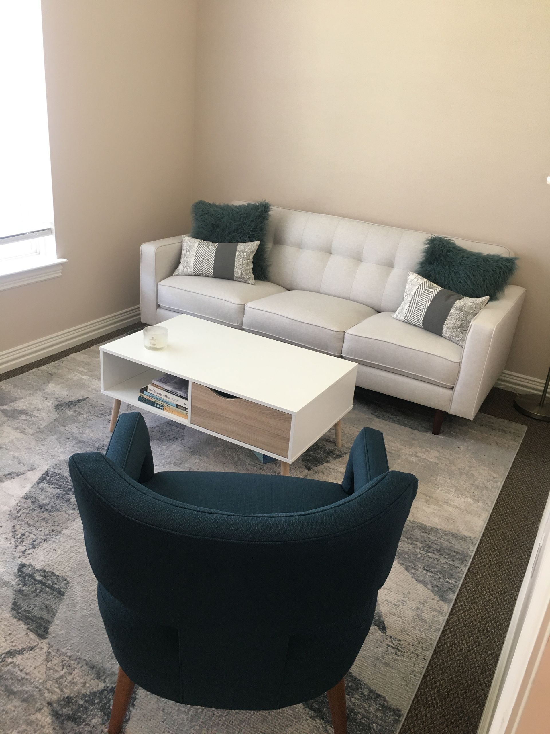 A living room with a couch , chair , coffee table and rug.