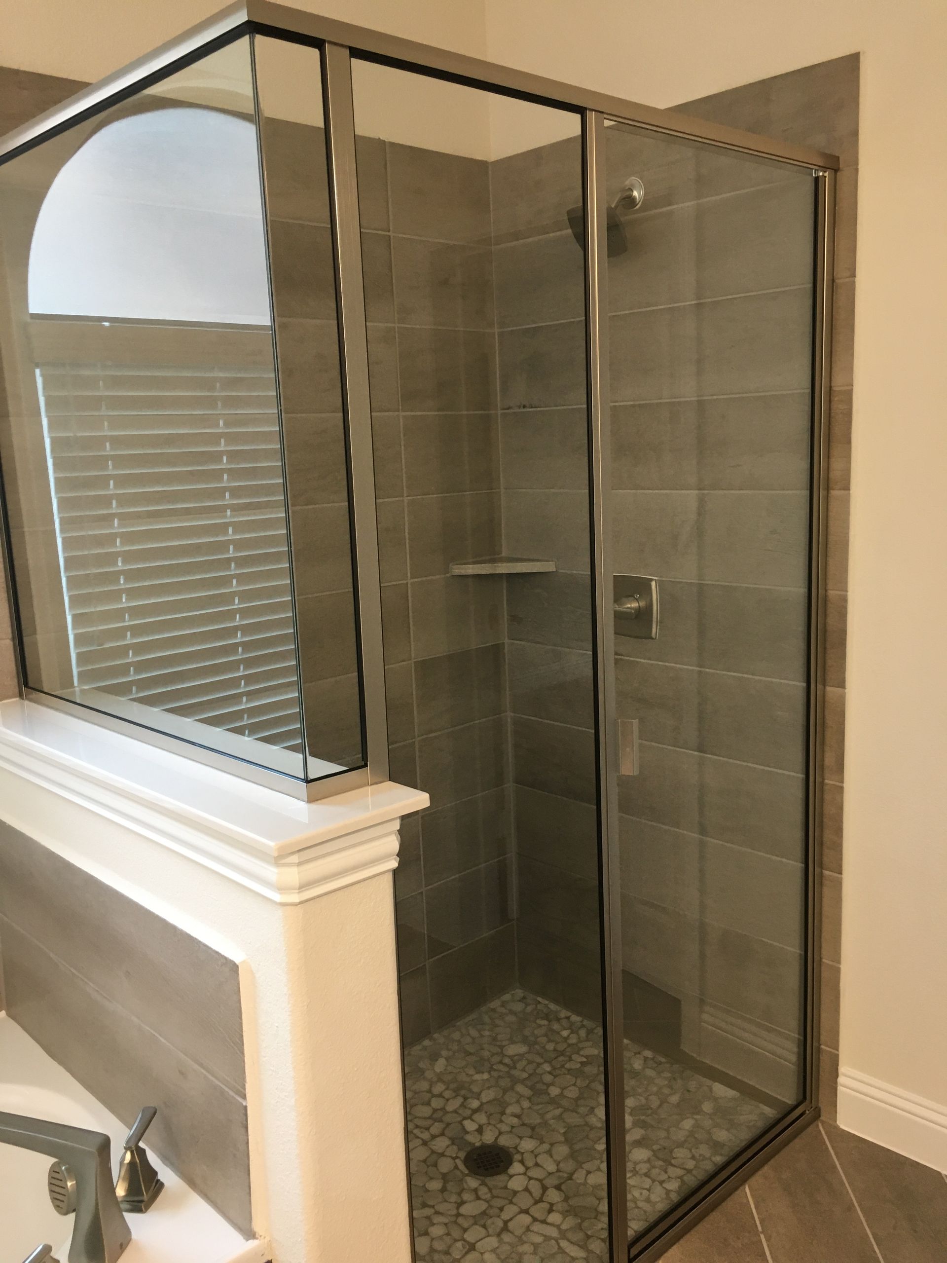 A bathroom with a walk in shower with a glass door