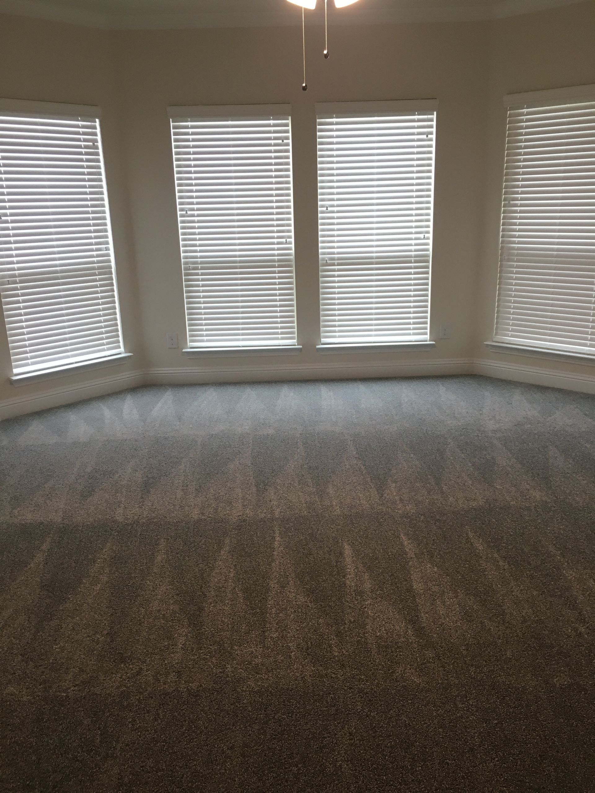 An empty living room with a lot of windows and blinds.