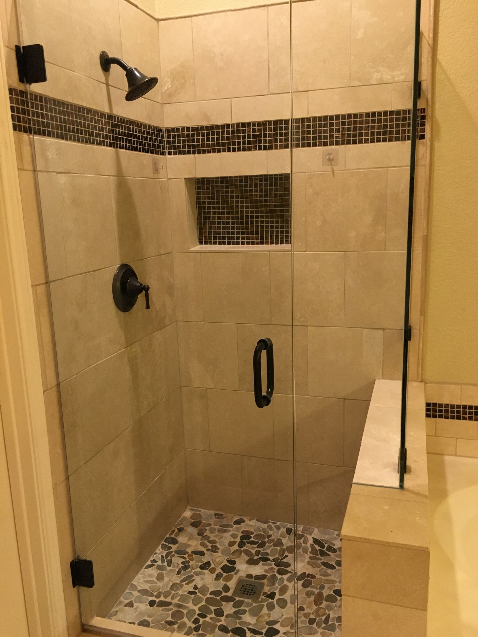 A bathroom with a walk in shower with a glass door