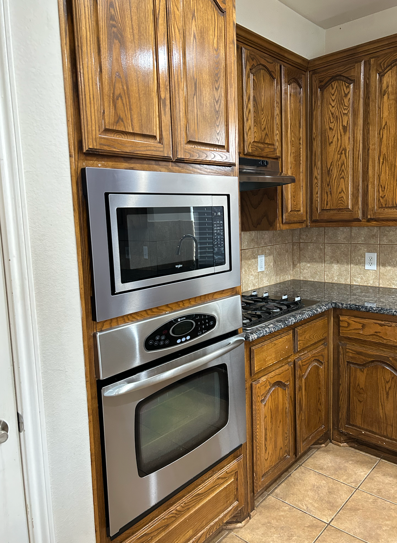 A kitchen with stainless steel appliances and wooden cabinets.
