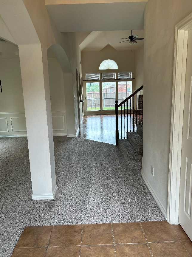 A hallway in a house with a staircase and a ceiling fan.